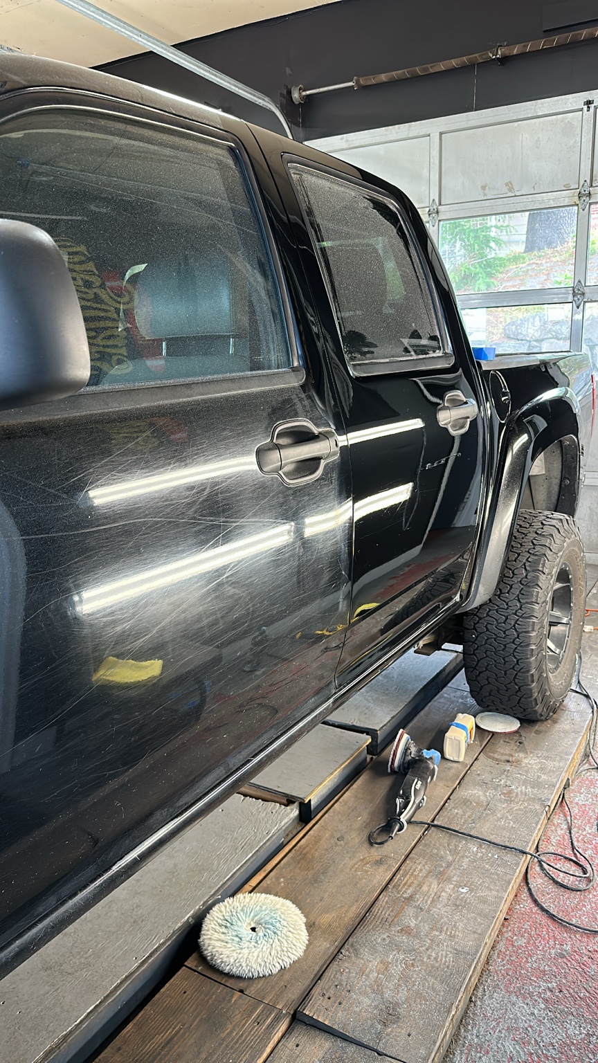 Black truck showing paint defects before a two-stage paint correction